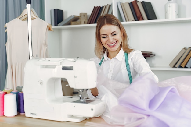 Woman sitting in studio and sew cloth