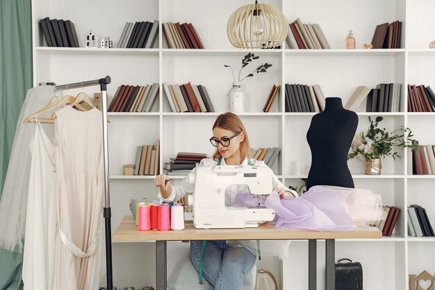 Woman sitting in studio and sew cloth