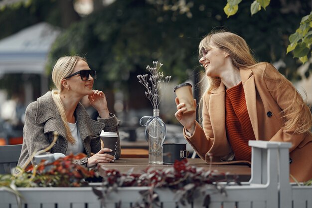 Woman sitting in a summer city and drinking coffee