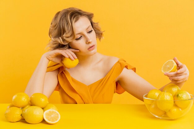 Женщина сидит за столом с миской лимона