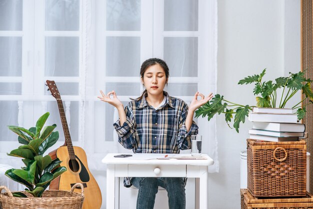 A woman sitting at the table working at the table and making a sign with a hand OK