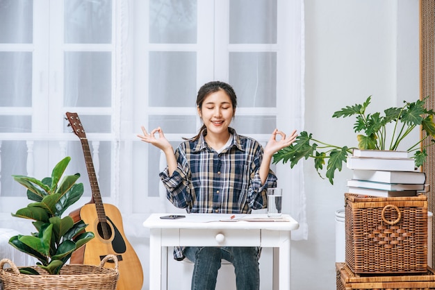 A woman sitting at the table working at the table and making a sign with a hand OK