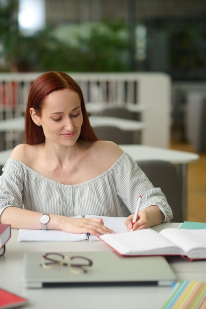 ノートに書くテーブルに座っている女性