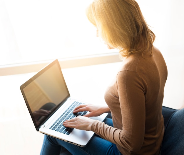 Free photo woman sitting and using laptop