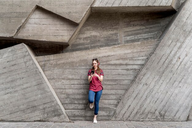 Woman sitting next to wall while checking mobile