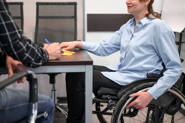 Free photo woman sitting in wheelchair at the desk