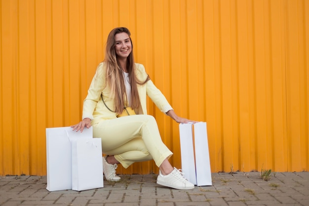 Woman sitting next to white shopping bags