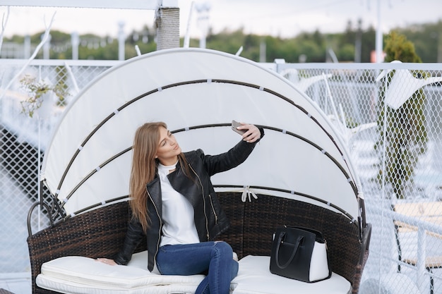 Free photo woman sitting in a wicker armchair with umbrella making an auto photo