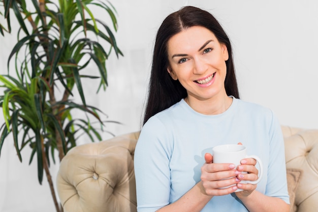 コーヒーカップとソファの上に座っている女性