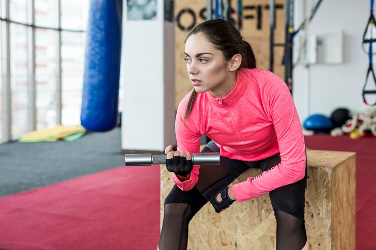 Woman sitting with dumbbell and exercising