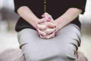 Free photo woman sitting with hands together on lap while praying