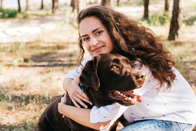 Foto gratuita donna che si siede con il suo cane in natura