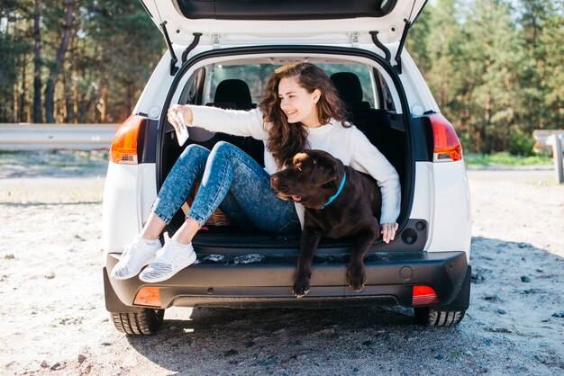 Женщина сидит со своей собакой в открытом багажнике