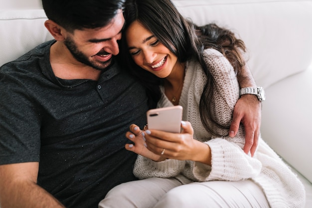 Woman sitting with his boyfriend sitting on sofa using cellphone