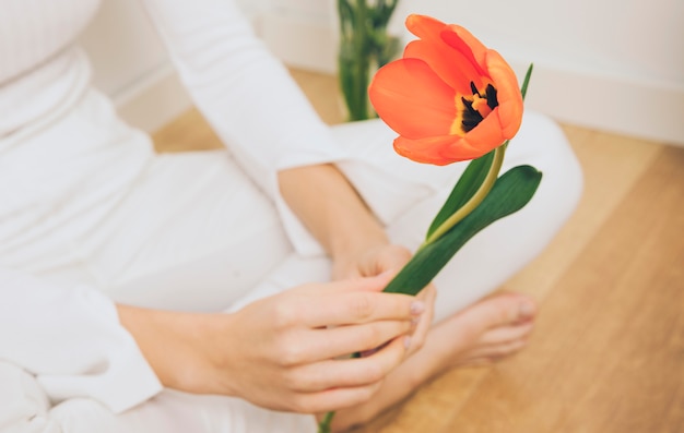 Woman sitting with tulip on floor 