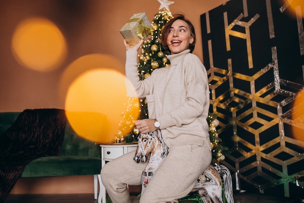 Woman sitting on wooden pony chair by the christmas tree