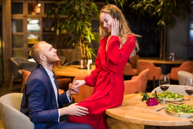 Woman sitting on wooden table and holding hand of man