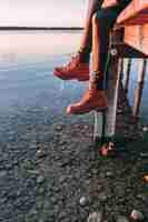 Free photo woman sitting on wooden walkway over lake