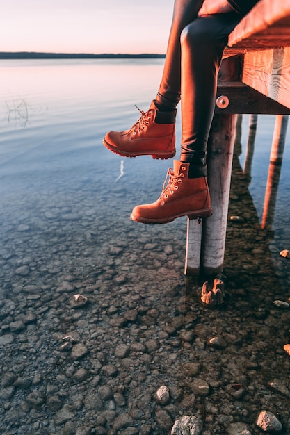 woman sitting on wooden walkway over lake