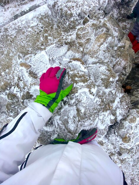 Женщина в лыжной одежде держит руку на ледяном камне в Карпатах, пик Тоака, Румыния
