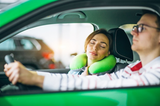 Женщина спит в машине на подушке и едет с мужем