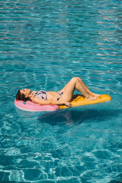 プールのインフレータブル・マットレスで寝る女性