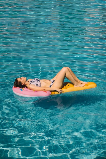 Woman sleeping on inflatable mattress in pool