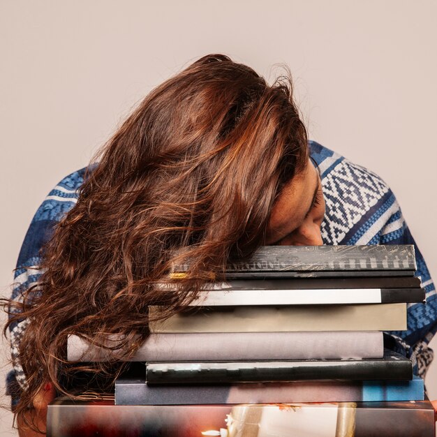Woman sleeping on pile of books