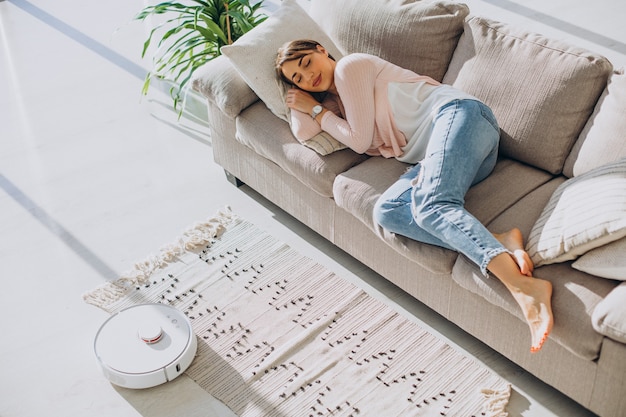 Free photo woman sleeping on sofa, vacuum cleaner doing housework