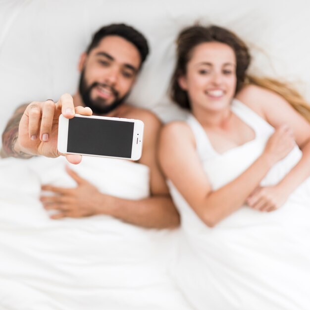 Woman sleeping with his wife holding mobile phone