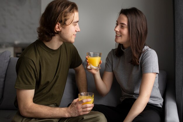 Woman smiling at boyfriend while holding glass of orange juice