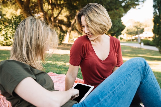 Woman smiling to friend with tablet