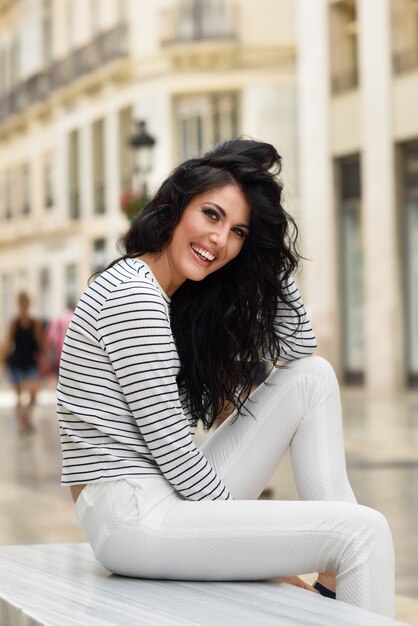 Foto gratuita donna sorridente e tenendo i capelli seduto su una panchina