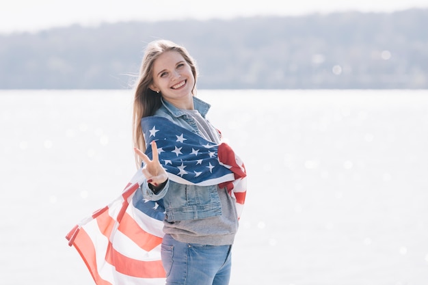 Foto gratuita donna che sorride e che esamina macchina fotografica avvolta nella bandiera americana