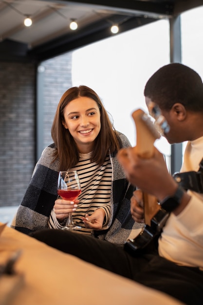 Free photo woman smiling and watching a man playing guitar at a party