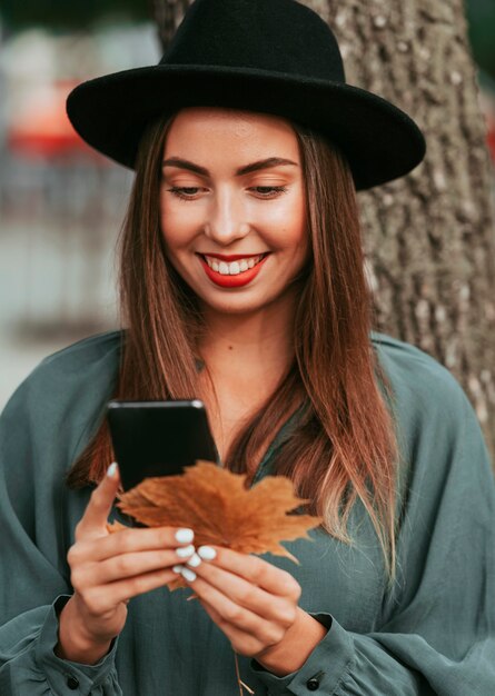 彼女の電話を見ながら笑顔の女性