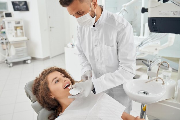 치아 색상 범위를 유지하는 남성 치과 의사 동안 웃는 여자