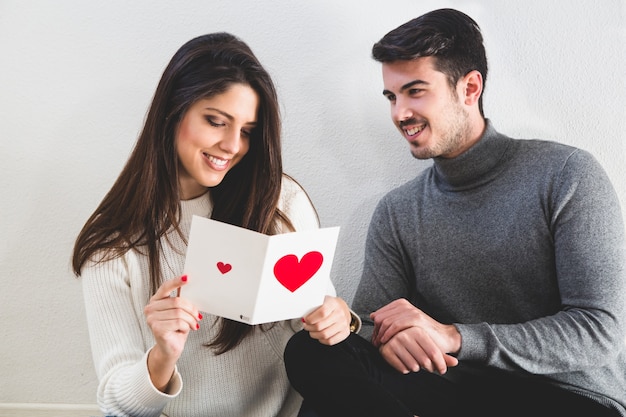 Woman smiling while reading a postcard with a heart