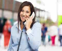 Free photo woman smiling while talking on the phone with blurred background