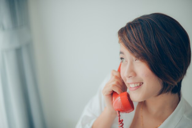 Woman smiling while talking on a red phone close up