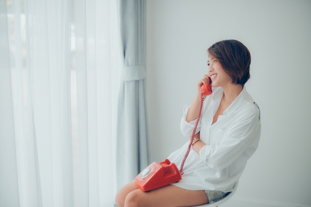 Женщина улыбается во время разговора по телефону красный