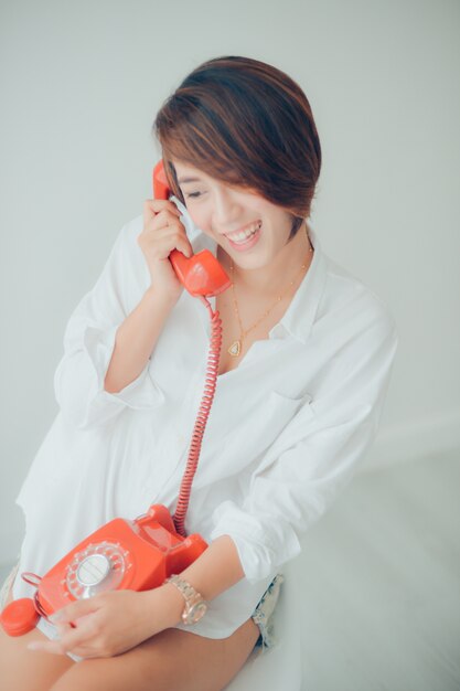 Woman smiling while talking on a red phone