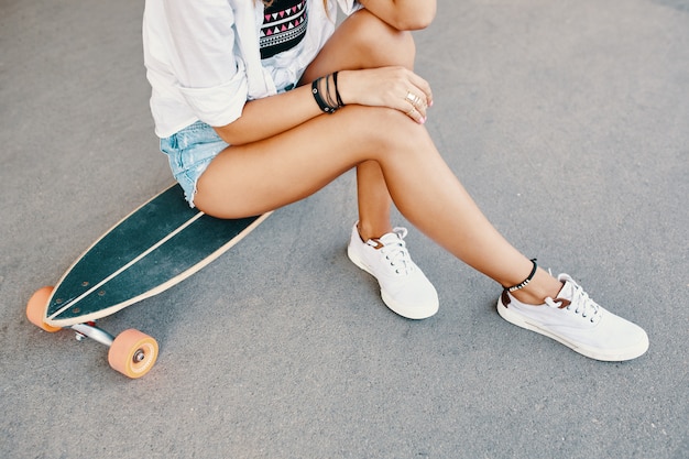 Женщина в кроссовках езда скейтборд открытый на асфальтовой поверхности.