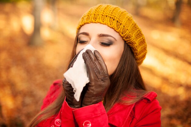 Woman sneezing in handkerchief at autumn