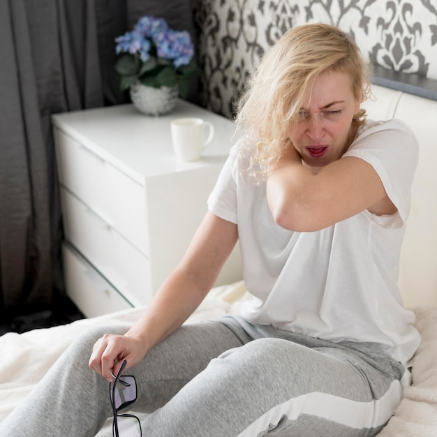 Woman sneezing and holding her glasses