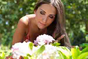 Free photo woman sniffing flower while sitting on grass