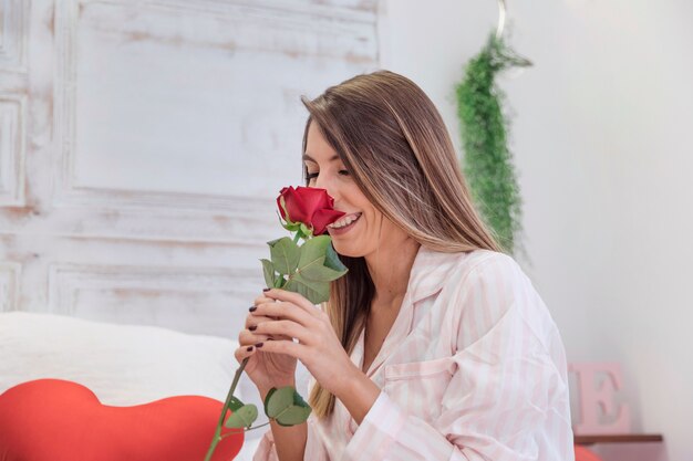 Woman sniffing rose on bed 