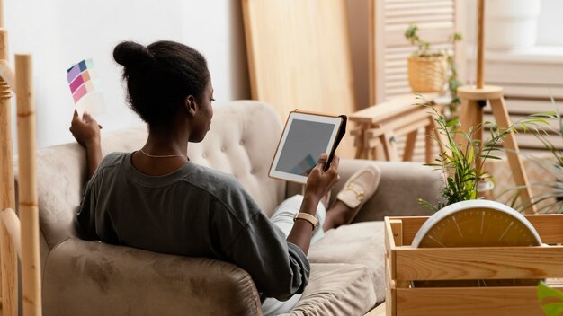컬러 팔레트와 태블릿을 사용하여 집을 재 장식 할 계획을 세우는 소파에 여자