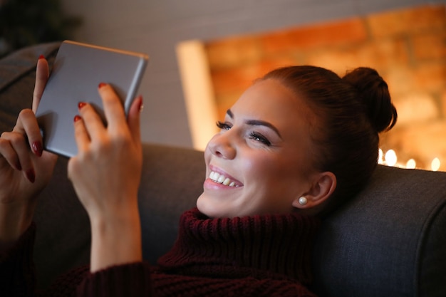 タブレットが付いているソファーの女性