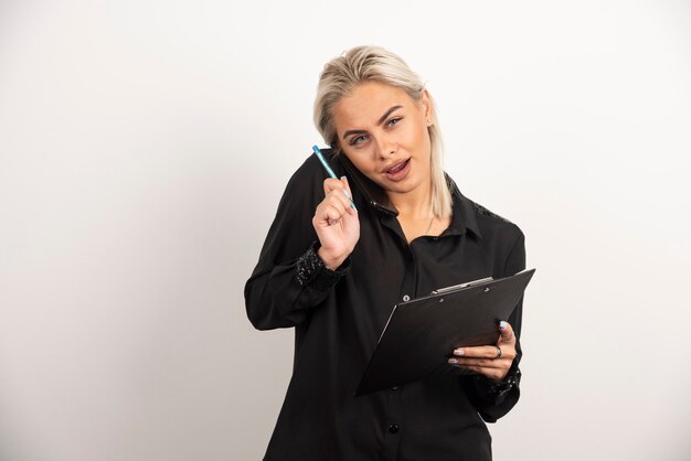 Woman speaking on mobile phone and holding a clipboard . High quality photo